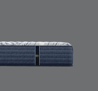 Side profile view of Serta iComfort mattress showing white and navy blue swirl-patterned pillow-top surface and deep navy blue quilted tufted base border