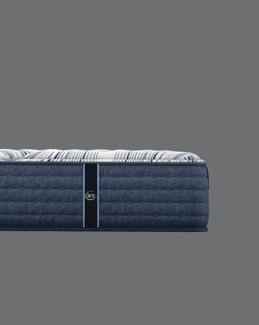 Side profile view of Serta iComfort mattress showing white and navy blue swirl-patterned pillow-top surface and deep navy blue quilted tufted base border