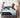 A couple making their bed with a Serta Antarctic mattress featuring a black and light blue border with All-Night Cooling Cooltex branding, on a grey upholstered bed frame