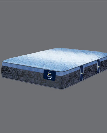 Full angled view of Serta Classic Latex mattress displaying soft blue plush tufted top and deep navy blue floral-patterned base with Classic Latex brand label on grey background