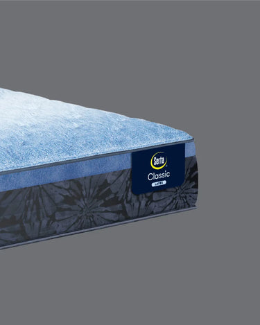 Corner close-up of Serta Classic Latex mattress highlighting the soft blue plush top layer and navy blue floral tie-dye patterned border with Classic Latex brand label