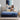 Mother reading a book while a child jumps happily on a Serta Classic Latex mattress with blue top and navy floral-pattern border on a beige upholstered bed frame