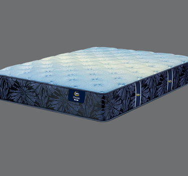 Angled view of Serta Classic Plus mattress displaying light blue tufted sleep surface and deep navy blue floral-pattern side border on a grey background