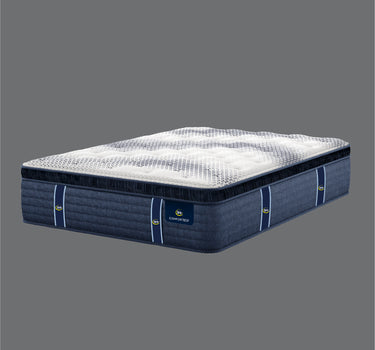 Full angled view of Serta iComfort Eco mattress displaying white geometric star-quilted pillow-top and navy blue quilted base with brand label on a grey background