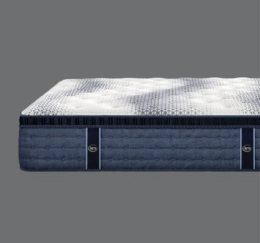 Side profile view of Serta iComfort Eco mattress showing white geometric star-patterned pillow-top surface and deep navy blue quilted base border