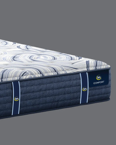 Corner close-up of Serta iComfort mattress highlighting the white and navy blue swirl-patterned pillow-top and deep navy blue quilted base with iComfort brand label