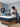Couple in a blue-toned bedroom with a woman sitting on a Serta iComfort mattress featuring white and navy swirl-patterned fabric on a wooden bed frame