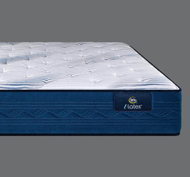 Side profile view of the Serta iLatex mattress showcasing its thick white tufted pillow top and deep navy blue wave-patterned quilted border