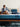 A couple relaxing on a Serta iPedic mattress with blue quilted sides, set on a wooden bed frame in a stylish bedroom