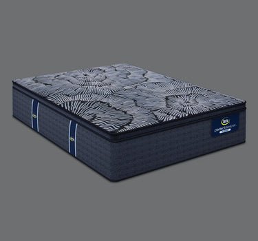 Angled view of Serta Perfect Sleeper Hybrid mattress displaying bold navy and grey floral radial-patterned pillow-top surface and solid navy blue base with brand label