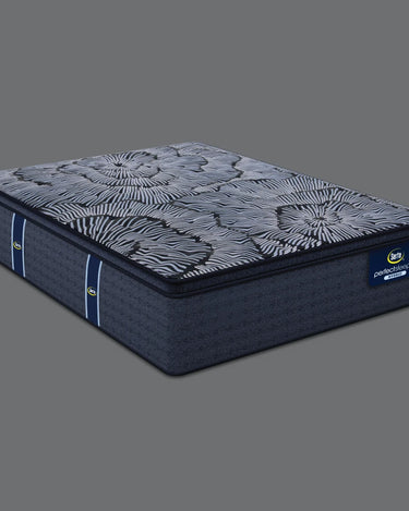 Angled view of Serta Perfect Sleeper Hybrid mattress displaying bold navy and grey floral radial-patterned pillow-top surface and solid navy blue base with brand label