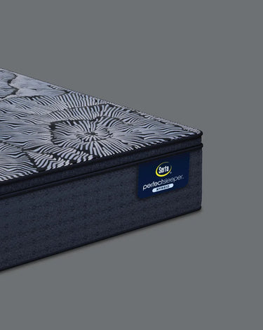 Corner close-up of Serta Perfect Sleeper Hybrid mattress highlighting the floral radial-patterned pillow-top layer and solid navy base with Perfect Sleeper Hybrid brand label