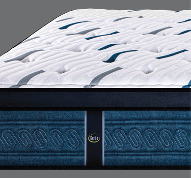 Corner close-up of Serta Perfect Sleeper mattress highlighting the white dash-patterned pillow-top layer and medium blue oval chain-stitched border with Serta brand label