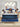 Happy family with two children playing on a Serta Perfect Sleeper mattress with white dash-quilted top and blue oval-patterned border on a navy upholstered bed frame