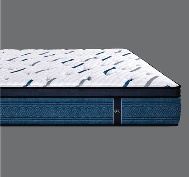 Side profile view of Serta Perfect Sleeper mattress showing white dash-pattern quilted pillow-top surface and medium blue oval chain-patterned base border on a grey background