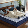 Couple sleeping comfortably on a Serta PerfectSpine mattress with blue wave-pattern fabric on a wooden bed frame in a modern bedroom
